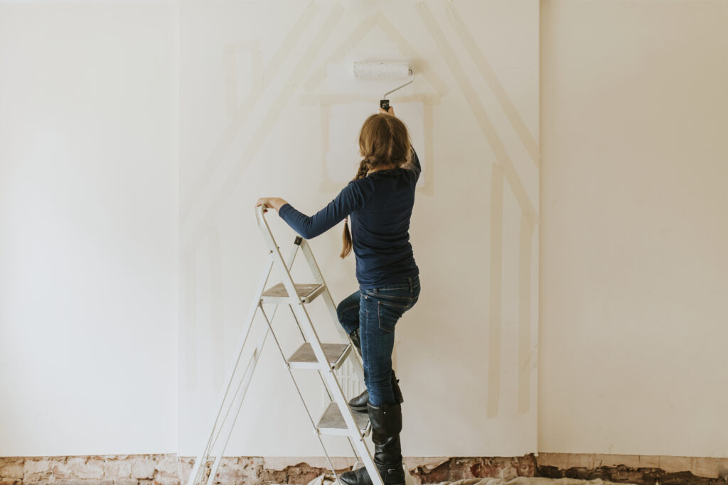 A lady painting her own home, instead of hiring interior painting services.
