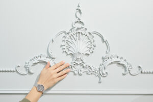 A person inspecting the work done by an exterior house painter on some of the ornaments on her home's exterior walls. 
