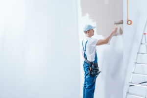 A painter who is skilled in exterior painting services, painting the walls of a home. 