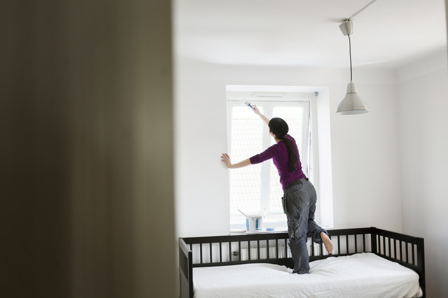 A woman who has opted for DIY painting instead of performing an online search for 'painters near me.'
