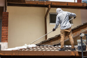 A professional painting service employee painting the roof of a home. 