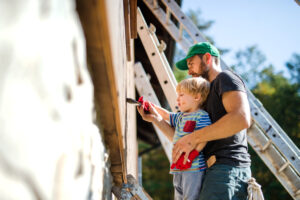 A father and child engaging in summer exterior paintwork.