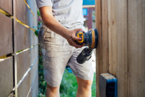 A person performing DIY siding repair.