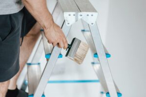 One of the painters near me climbing a ladder to paint a wall.