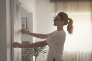 A woman hanging a painting on her freshly painted walls, after performing an online search for: "the best painters near me."