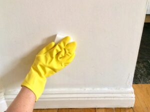 One of Wichita's professional residential painting contractors cleaning a wall before they begin the painting process.