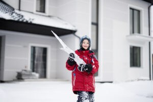 A child playing outside during winter, which is not the best time to paint outside.
