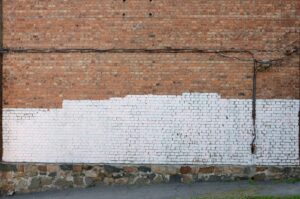 Residential house wall undergoing exterior painting work.