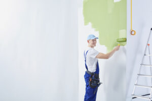A professional painter painting a home's interior after determining when not to paint outside.