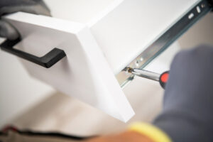 A kitchen cabinet paint service contractor re-installing a kitchen cabinet drawer after disassembling it for painting.