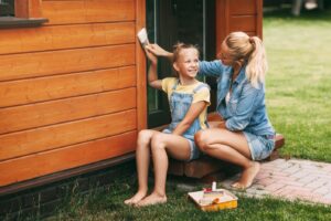Mom teaches daughter to paint their house siding, after researching: Can You Paint Hardie Board? 