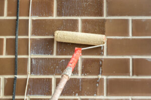An exterior brick painter prepping a wall with primer before painting it.