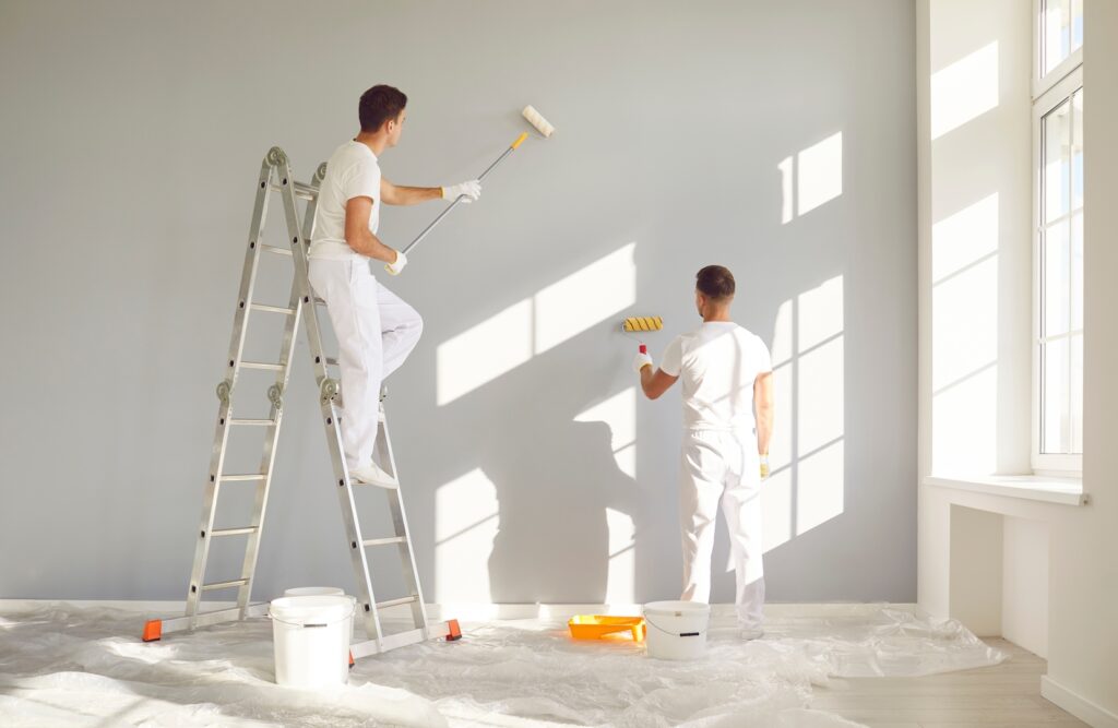 A team of painting contractors Wichita KS painting a wall together.
