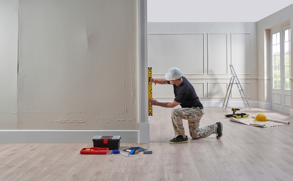 A construction worker using a level tool in a freshly renovated interior, surrounded by professional equipment—highlighting the meticulous planning and execution that underscores how commercial and residential painting projects are not the same in terms of scale, standards, and techniques.

