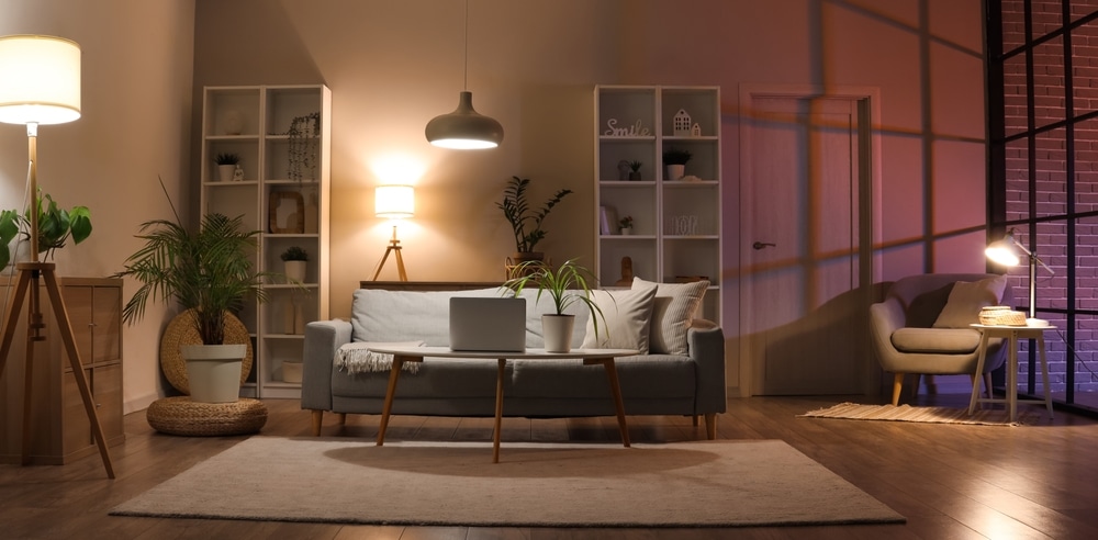 A cozy modern living room with varied lighting temperatures casting warm and cool tones on the walls, subtly illustrating the concept of a paint color heat absorption chart through visual contrast in wall colors and lighting.

