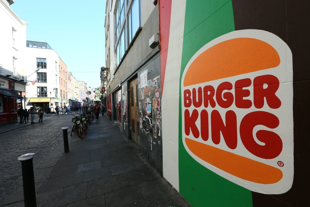 Vibrant Burger King logo painted on the exterior wall of a city building along a busy urban street, representing eye-catching commercial painting used for brand visibility and outdoor advertising.

