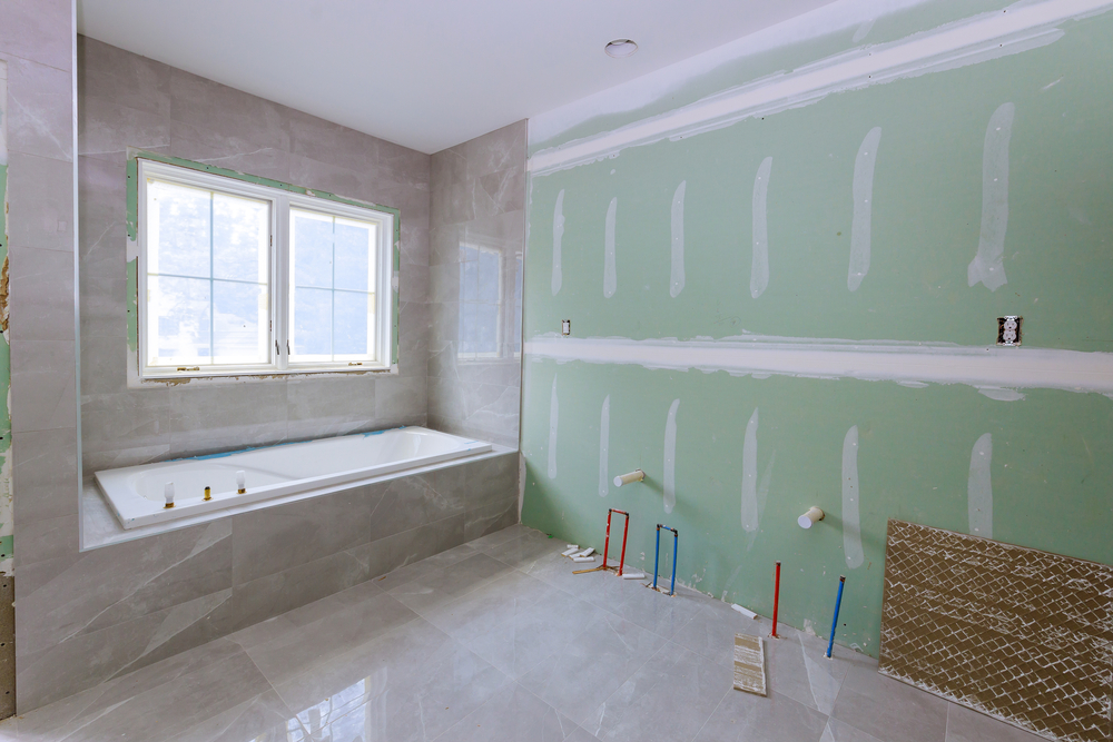 Bathroom under construction with exposed plumbing and tile work, illustrating one of the major types of renovations in home remodeling.