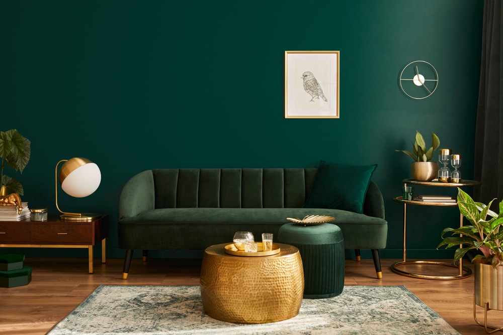 Stylish living room with dark green walls, velvet sofa, gold accents, and modern decor—showcasing elegant interior design trends in modern renovations.
