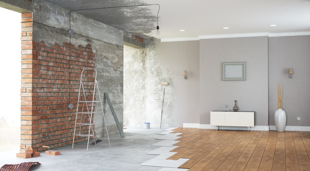 Partially renovated living room showing exposed brick, unfinished walls, and new flooring installation—visually representing the stages involved in answering "how long does home renovation take."
