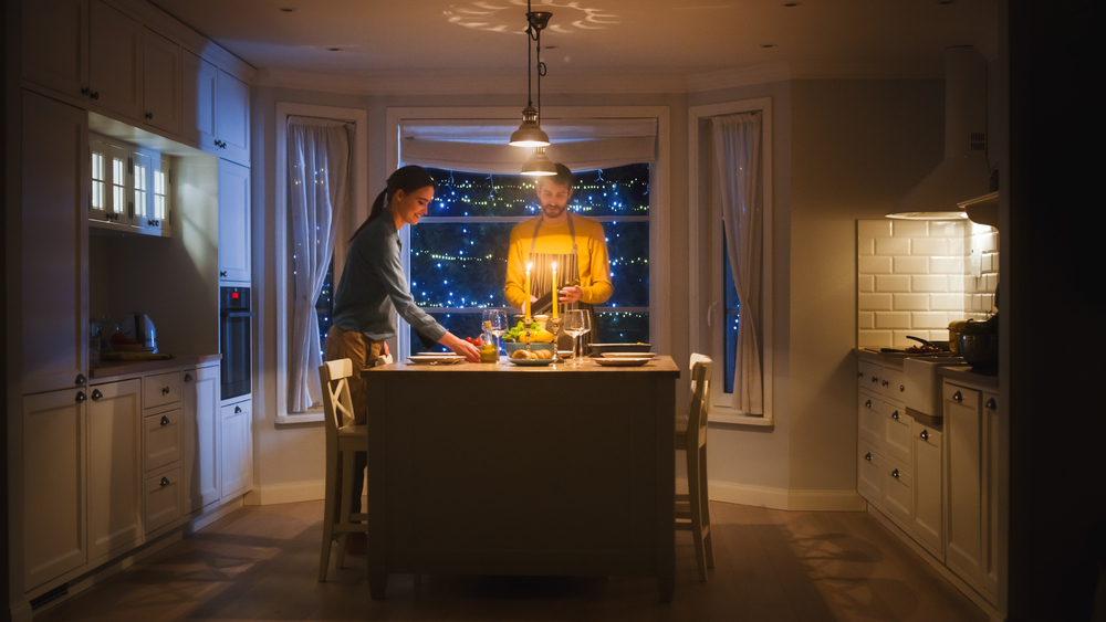 Modern kitchen with couple dining at night, illustrating the question: does remodeling a kitchen increase home value through upgraded design and functionality?