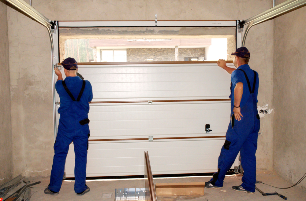 Two workers installing a new garage door — one of the best home improvements to increase value by boosting curb appeal and security.
