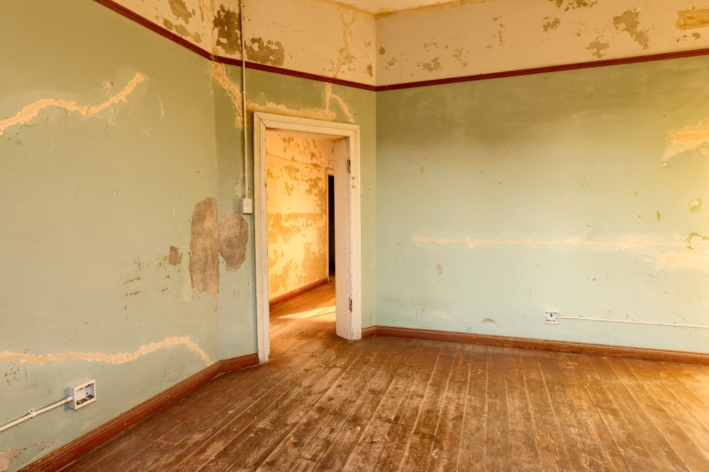 Old interior room with peeling walls and faded paint, showing damage and poor results that answer the question 'can you use exterior paint inside' with no.