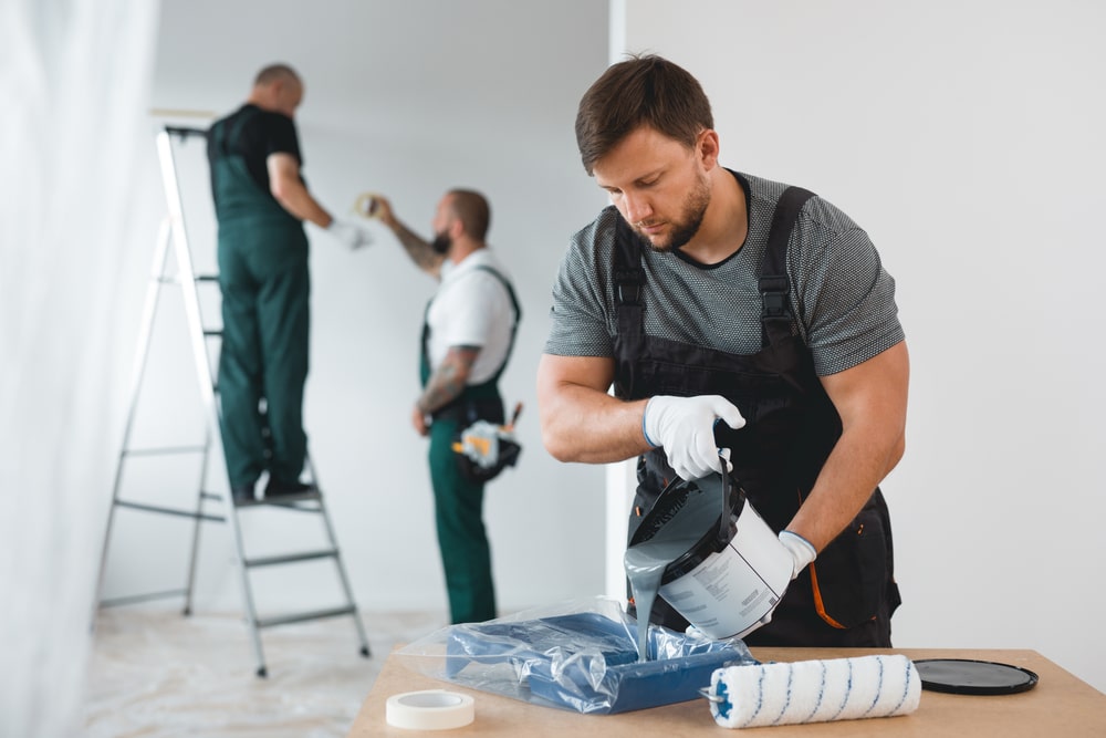 Team of professional painters preparing tools and paint for an interior renovation, showcasing the quality and expertise offered by the best painting company